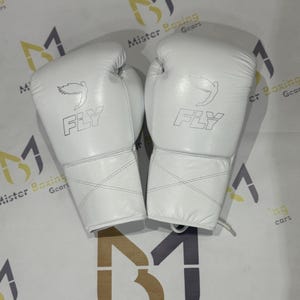 May include: A pair of white boxing gloves with the word "FLY" printed on them. The gloves have a stylized bird graphic above the word "FLY". The gloves are made of a smooth material and are designed for boxing.