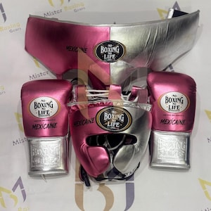 Könnte beinhalten: Ein Boxset bestehend aus einem Tiefschutz, einem Kopfschutz und zwei Boxhandschuhen in Metallic-Pink und Silber. Jedes Teil zeigt einen schwarz-goldenen ovalen Aufnäher mit dem Text NO BOXING NO LIFE und dem Wort MEXICAINE in Schwarz.
