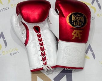 Op de afbeelding: Paar witte en rode bokshandschoenen. De handschoenen hebben de tekst "NO BOXING NO LIFE" en een gouden logo. De handschoenen hebben een vetersluiting en zijn gemaakt van leer. Voor boksen.