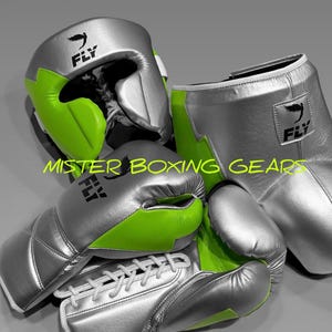 Könnte beinhalten: Silberne Boxhandschuhe, Kopfschutz und Fußschützer mit neongrünen Akzenten. Die Ausrüstung trägt das "FLY"-Logo. Der Text "MISTER BOXING GEAR" ist ebenfalls sichtbar.