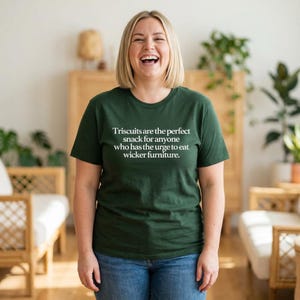 May include: Dark green t-shirt with the text "Triscuits are the perfect snack for anyone who has the urge to eat wicker furniture." The shirt is paired with blue jeans.