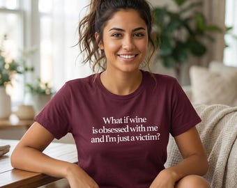 Puede incluir: Camiseta burdeos con cuello redondo y el texto blanco: "¿Y si el vino está obsesionado conmigo y yo solo soy una víctima?" La camiseta la lleva una persona.