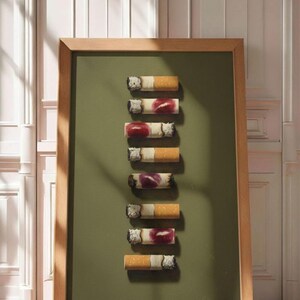A large framed print of the lipstick cigarettes artwork leaning against a white paneled wall on a wood floor.