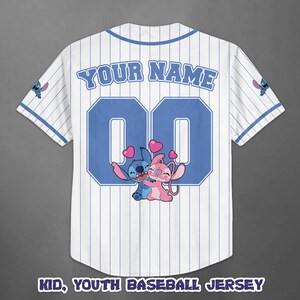 Op de afbeelding: Wit honkbalshirt met blauwe krijtstrepen, met de tekst "YOUR NAME" boven een grote blauwe "00". De trui heeft een cartoonafbeelding van Stitch en Angel die elkaar omhelzen, met harten. De tekst "KID, YOUTH BASEBALL JERSEY" staat onderaan.