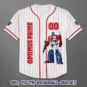 Op de afbeelding: Wit honkbalshirt met rode krijtstrepen, met de tekst "OPTIMUS PRIME" aan de linkerkant en het nummer "00" aan de rechterkant. Een afbeelding van Optimus Prime staat op de voorkant. De tekst "KID, YOUTH BASEBALL JERSEY" staat onderaan.