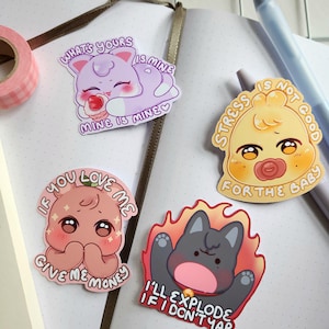 Può includere: Una collezione di adesivi colorati con illustrazioni di cartoni animati e testo. Gli adesivi presentano un gatto viola, un pulcino giallo con un ciuccio, una creatura rosa e un gatto grigio in fiamme. Il testo include frasi come "What's yours is mine" e "I'll explode if I don't yap."