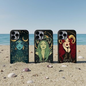 Puede incluir: Tres fundas negras para teléfono con ilustraciones temáticas del zodíaco se exhiben en una playa de arena. Las fundas presentan ilustraciones detalladas de figuras celestiales, incluida una mujer con cabello azul, una mujer con cabello verde y una mujer con cabello rojo. Las palabras "CANCER" y "ARIES" son visibles.