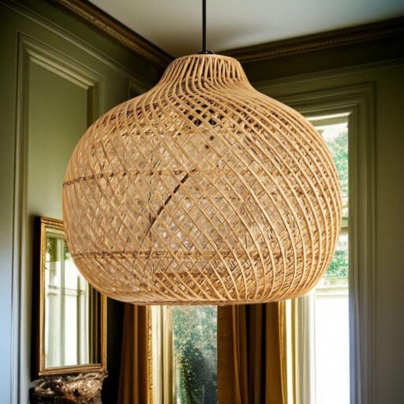May include: A large, woven rattan pendant light. The light has a bulbous shape with a wide, open base and a narrower top. The natural tan colour of the rattan creates a warm glow. The fixture hangs from a black cord, suitable for a living room or dining area.