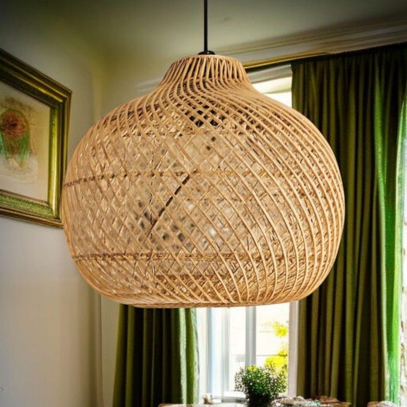 May include: A woven rattan pendant light. The light has a bulbous shape with a wide base and a narrower top. It is suspended from a black cord and is made of natural-coloured rattan.