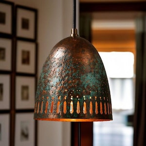 Könnte beinhalten: Kupferfarbene Pendelleuchte mit Patina-Finish. Der kuppelförmige Schirm hat eine strukturierte Oberfläche und vertikale Aussparungen. Die Leuchte hängt an einem schwarzen Kabel. Geeignet für die Innenbeleuchtung, ca. 30 cm Durchmesser.
