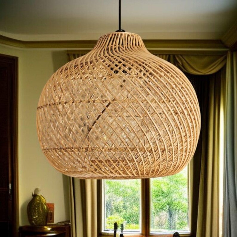 May include: A large, woven rattan pendant light. The light has a spherical shape with a wide base and a narrower top, suspended from a black cord. The natural beige colour of the rattan creates a warm, inviting aesthetic, suitable for interior decor.