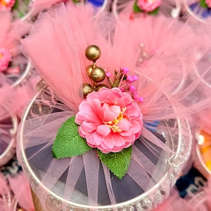 May include: A white ceramic mug with a black handle and the text "But First, Coffee" in a bold, black font. The mug is set against a blurred background, suggesting a cozy setting.