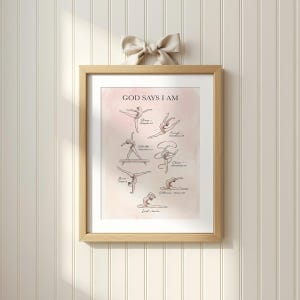 Puede incluir: Un estampado enmarcado con el texto "GOD SAYS I AM" e ilustraciones de poses de gimnasia. El estampado tiene un fondo rosa claro y está en un marco de madera clara. Un lazo beige está sujeto a la parte superior del marco.