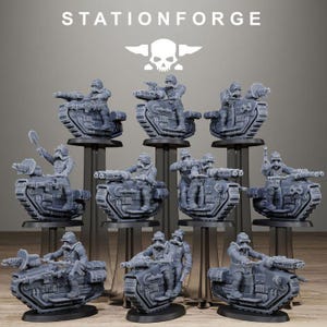 May include: A set of grey miniature tanks with soldiers, displayed on black stands. The tanks feature detailed mechanical designs and are equipped with cannons. The text "STATIONFORGE" is at the top, along with a skull and wings logo.