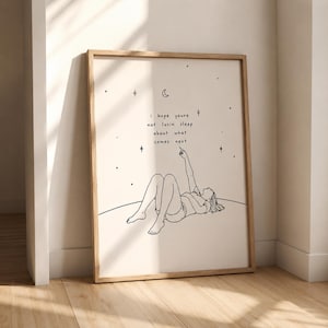 May include: A framed art print with a minimalist line drawing of a person lying down and pointing upwards. The print has the text "i hope youre not losin sleep about what comes next" with stars and a crescent moon.