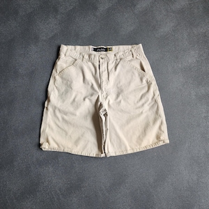 May include: Khaki-colored shorts with multiple pockets and a button closure. The shorts have a relaxed fit and a faded appearance. The brand name "chakis" is visible on a tag near the waistband. These shorts are suitable for casual wear.