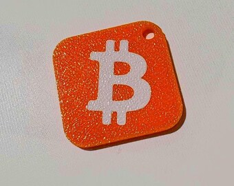 May include: Orange, square-shaped Bitcoin keychain with a white Bitcoin symbol. The keychain has a textured surface and a small hole at the top for attachment. The Bitcoin symbol is centered on the orange background.