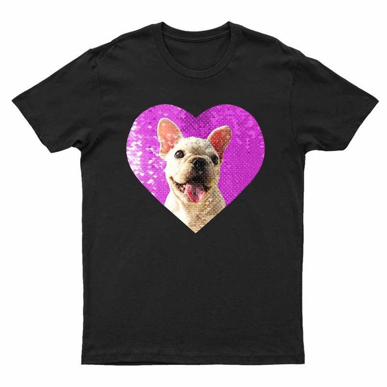 Puede incluir: Camiseta negra con un bulldog franc&eacute;s sonriendo dentro de un coraz&oacute;n rosa. El perro tiene un pelaje de color claro y su lengua es visible. El coraz&oacute;n tiene un aspecto texturizado y brillante. Prenda de vestir informal con tem&aacute;tica de mascotas.