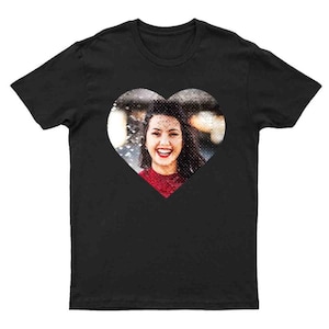 Puede incluir: Camiseta negra con un dise&ntilde;o en forma de coraz&oacute;n. El dise&ntilde;o presenta una fotograf&iacute;a de una persona sonriente que lleva una camiseta roja. La imagen est&aacute; centrada en la parte delantera de la camiseta.