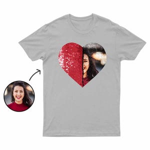 Puede incluir: Una camiseta gris claro con un dise&ntilde;o de coraz&oacute;n. El lado izquierdo del coraz&oacute;n es de lentejuelas rojas, y el lado derecho presenta una foto de una persona sonriendo. Una peque&ntilde;a foto de la persona est&aacute; en la esquina inferior izquierda.