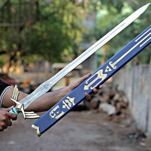 May include: A silver sword with a detailed hilt and a blue scabbard with gold accents. The sword is held next to its scabbard, showcasing the design. The scabbard has a gold emblem on the end.