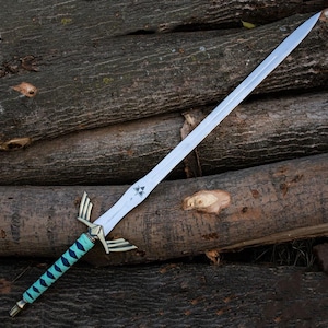 May include: A silver sword with a pointed blade and an ornate hilt. The hilt has gold-coloured details and a turquoise grip. The blade features a triangular symbol near the hilt. The sword is displayed on a pile of wooden logs.