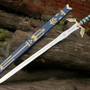May include: A silver sword with a gold hilt and a blue and gold scabbard. The sword has a detailed design on the hilt and blade. The scabbard is blue with gold accents. The sword is lying on a log.
