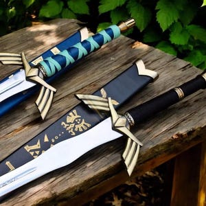 May include: Three decorative swords with gold detailing and sheaths. The swords have silver blades and black handles. One sword has a blue sheath, another a black sheath with gold designs, and the third a blue and teal handle.