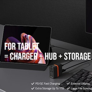 May include: A black tablet with the text "FOR TABLET = CHARGER + HUB + STORAGE" is connected to a black and orange charger hub. A black keyboard is in the foreground. Features include PD/QC fast charging and external display.