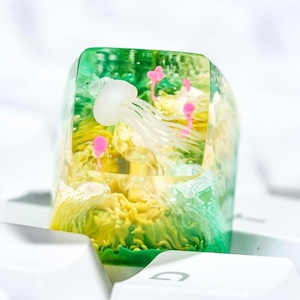 May include: A white ceramic mug with a black handle and the text "But First, Coffee" in a handwritten style. The mug is on a white surface. The mug is 4 inches tall.