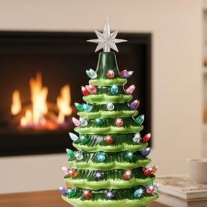 May include: A ceramic Christmas tree with colorful lights and a star topper. The green tree has multiple tiers and is decorated with red, blue, green, and yellow lights. The tree sits on a wooden table.