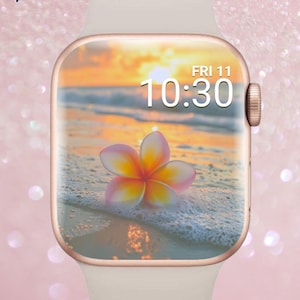 Peut inclure: Une montre connectée or rose avec un bracelet blanc affiche une scène de plage avec une fleur et l'heure 10h30. Le cadran de la montre présente un coucher de soleil sur l'océan. Les mots "Luxe Babe" sont dans le coin supérieur gauche.
