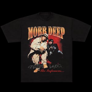 May include: Black t-shirt with a graphic of the hip-hop duo Mobb Deep. The design includes the band's name in orange, images of the two members, and the text "Prodigy" and "Havoc: The Infamous..." in white.