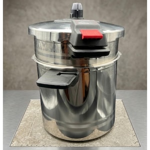 May include: A stainless steel pressure cooker with a polished finish, featuring a locking lid mechanism with a prominent red release button, black side handles, and horizontal decorative bands etched into the cylindrical body.