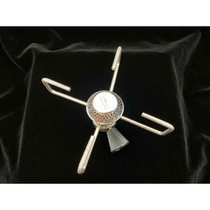 Puede incluir: Un hornillo de camping portátil de color plateado con un cabezal de quemador circular de superficie perforada, cuatro brazos de soporte metálicos extensibles y un mando de control estriado gris oscuro para ajustar el flujo.