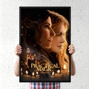 May include: A framed movie poster for Practical Magic 2 featuring the faces of two women in profile, a large house in the background, and several lit candles at the bottom. The title Practical Magic 2 is written in gold lettering in the center.