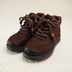 May include: A pair of brown leather ankle boots with dark brown soles and laces. The boots have a rounded toe and are lined with a soft, light brown material. The laces are secured with small wooden beads.