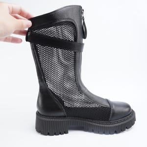 Puede incluir: Bota negra hasta la rodilla con un panel de malla y suela gruesa. La bota tiene cremallera, correa y puntera redondeada. La parte superior es de cuero y malla. La suela mide aproximadamente 3,8 cm de alto.
