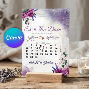 May include: A wedding Save The Date card with a calendar for December 2025, highlighting the wedding date. The card has a purple and white watercolour design, floral accents, and the names Alina & William. It is displayed on a wooden stand.