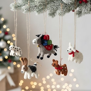 May include: A collection of handmade felt animal ornaments, including a Dalmatian, donkey, rabbit, deer, and dog. The donkey carries colorful packages. Each ornament hangs from a twine string, perfect for holiday decorating.