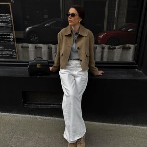 Woman in structured beige leather jacket with neutral tones and timeless capsule wardrobe look