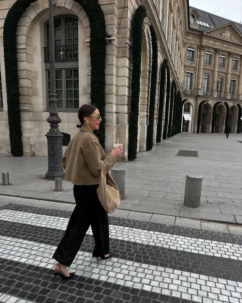 Female model walking in oversized beige leather jacket with neutral minimalist fashion look
