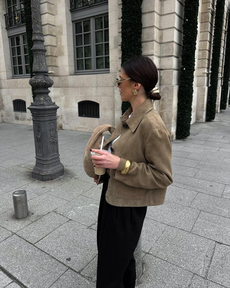 Woman walking in beige leather jacket with black trousers and quiet luxury outfit street style