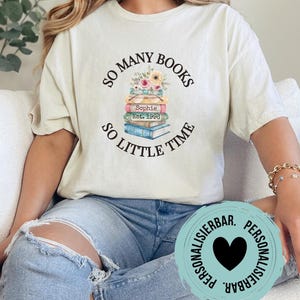 Könnte beinhalten: Cremefarbenes T-Shirt mit dem Text "SO MANY BOOKS SO LITTLE TIME" um einen Bücherstapel mit floralen Akzenten. Das Shirt enthält auch den Namen "Sophie" und das Jahr "Est. 1980".