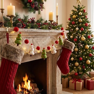Peut inclure: Une scène de Noël festive avec un sapin décoré, des chaussettes et une cheminée. Une guirlande avec des arbres de Noël en feutre et des pompons rouges est suspendue au-dessus de la cheminée. Deux bas rouges avec garniture en fausse fourrure sont accrochés.