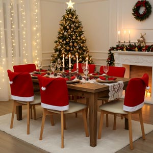 May include: A festive dining table set for Christmas. The table is set with red placemats, gold-rimmed plates, and wine glasses. Red chair covers shaped like Santa hats add a holiday touch. A decorated Christmas tree and fireplace complete the scene.