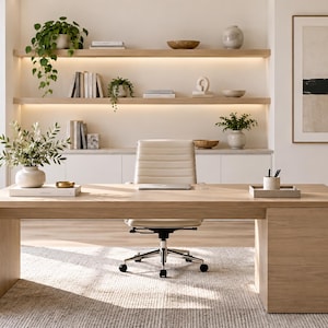 May include: A light oak wood desk with a rectangular top and a solid side panel base, paired with a cream-colored, ribbed, swivel office chair on wheels. The desk surface holds a white vase with greenery, a small gold bowl, and a tray with pens.