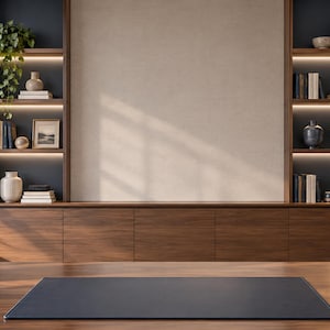May include: A wooden desk featuring a dark blue leather desk mat, a gold bowl, a dark blue pen holder, and stacked books. In the background, a wall unit with dark blue shelves, integrated lighting, and wooden cabinets displays various decor items.