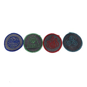 May include: Four circular embroidered patches featuring elemental symbols. Each patch has a dark gray fabric base with a distinct colored border and matching thread embroidery: blue water waves, green earth square, red fire flame, and teal air swirls.