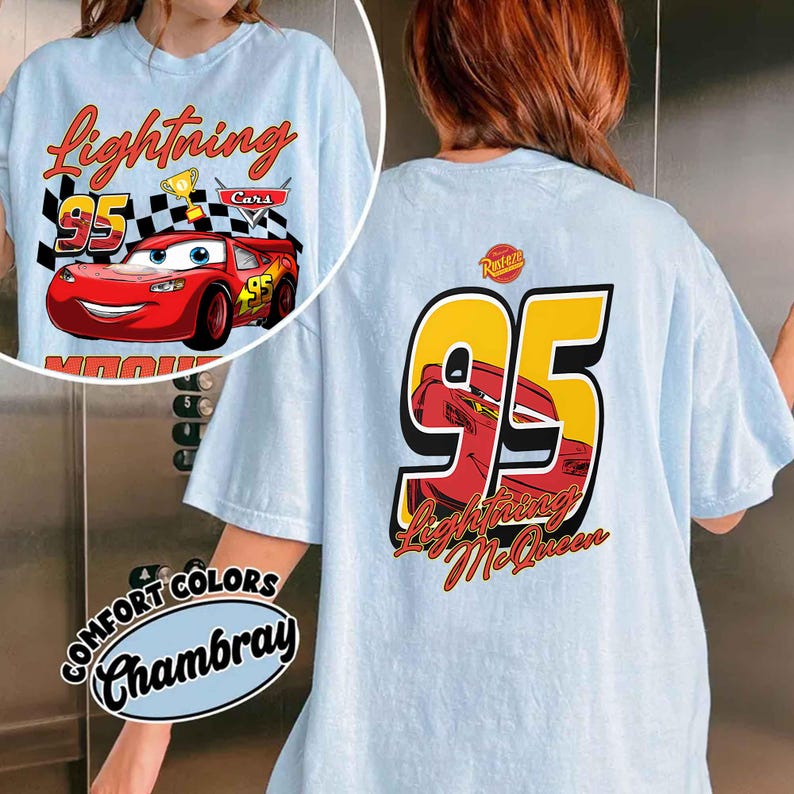 Może przedstawiać: Jasnoniebieska koszulka z Lightning McQueen z filmu Auta. Grafika z przodu zawiera Lightning McQueen, numer 95 i napis "Lightning". Tył koszulki ma dużą grafikę "95" z Lightning McQueen i napisem "Lightning McQueen".